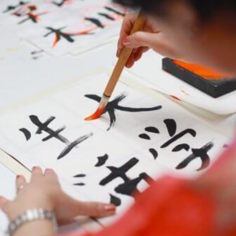 A person doing Japanese calligraphy to represent online Japanese language classes.